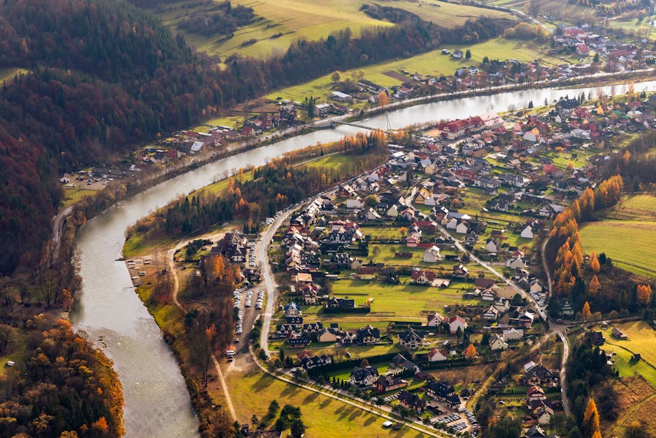 A scenic aerial image highlighting a tranquil riverside village amidst vibrant fall colors.